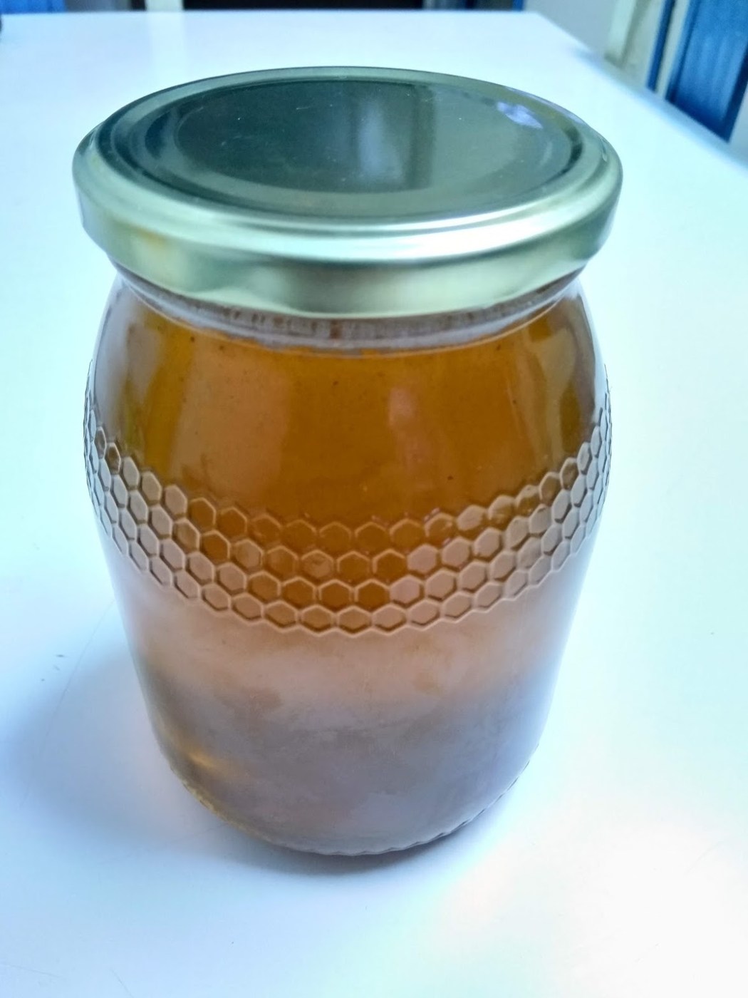 A glass jar of golden honey with a metal lid